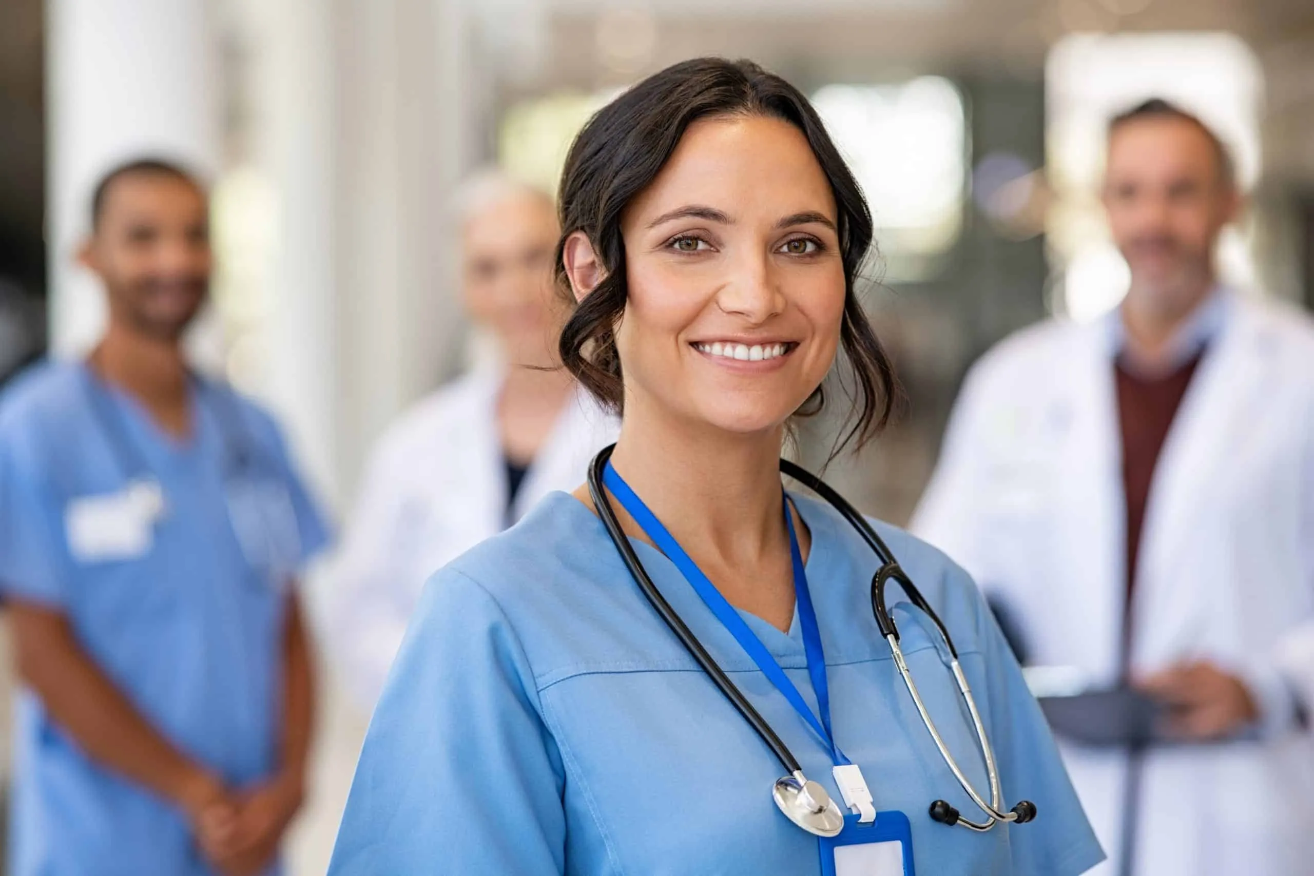 Infirmière souriante en uniforme bleu, stéthoscope au cou